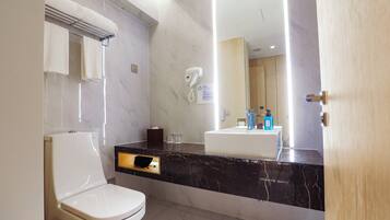 A modern bathroom with a toilet, a towel rack, a hairdryer, and a sink with a mirror above it.