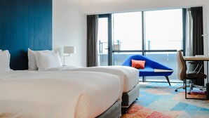 Une chambre d’hôtel avec un grand lit, un bureau, une chaise et une vue sur le balcon.