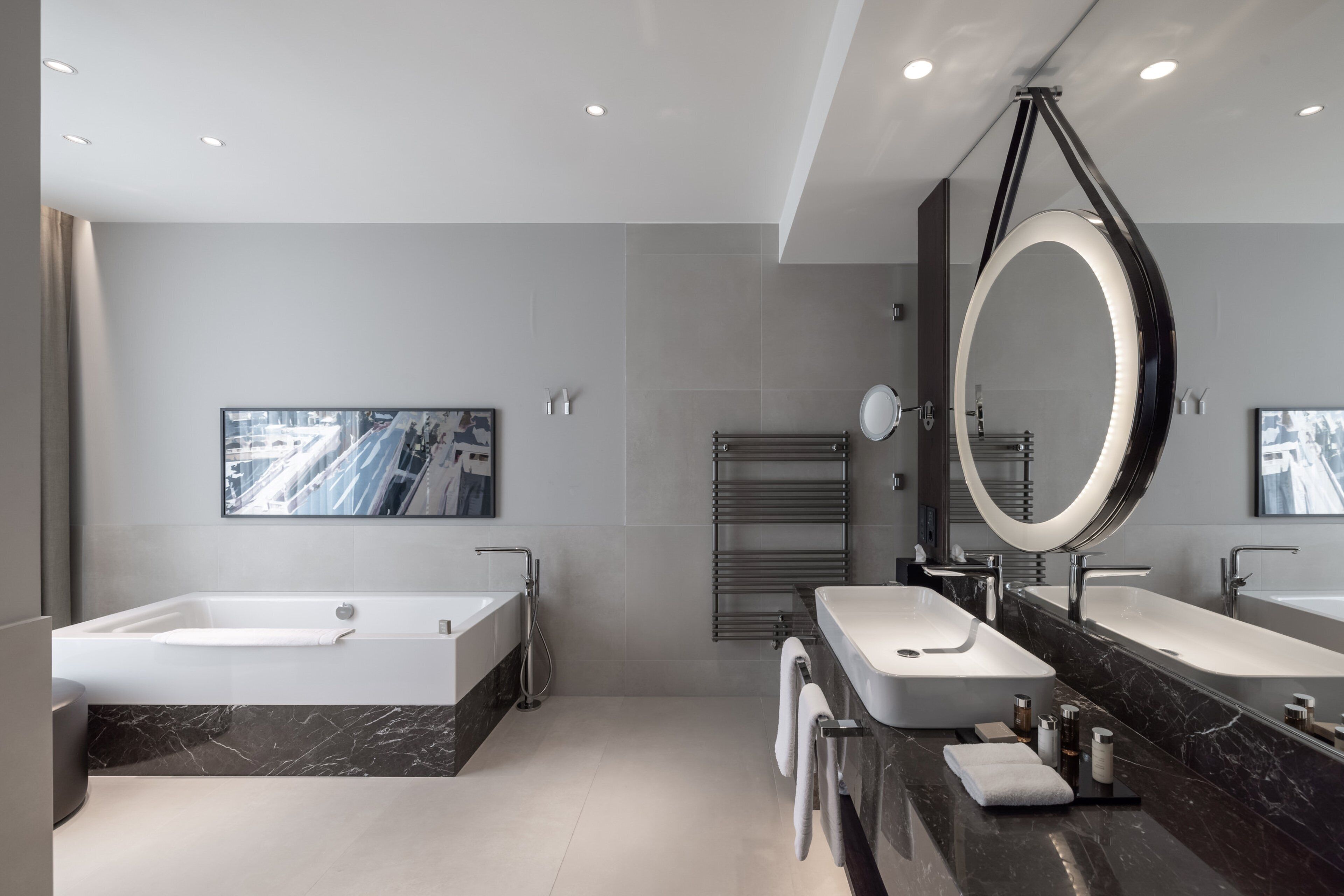Une salle de bain moderne avec deux vasques, un grand miroir et un porte-serviettes chauffant.