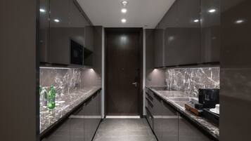 A modern kitchen with marble countertops, a microwave, and a coffee machine.