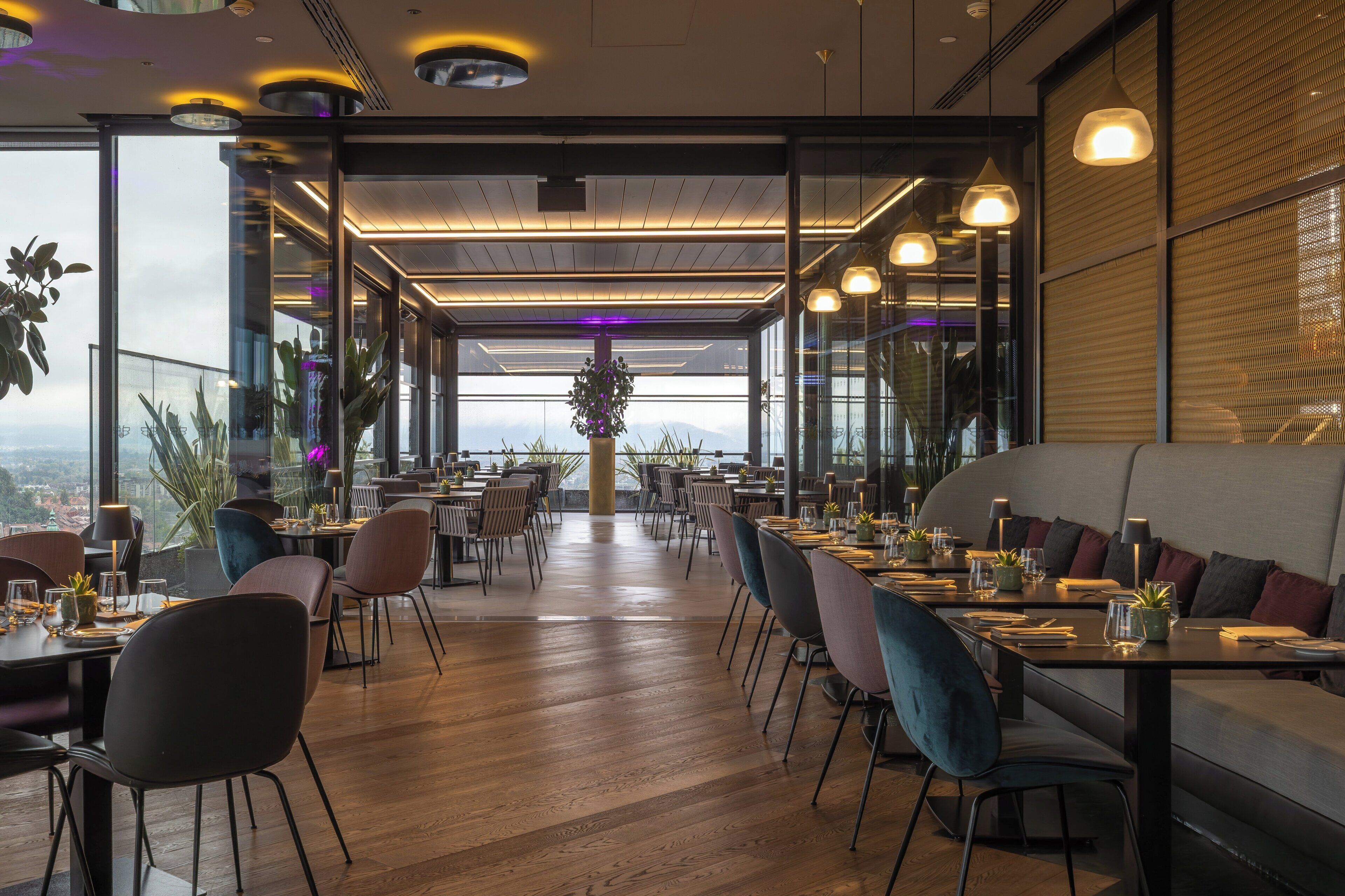 Um restaurante moderno com teto alto, piso de madeira e diversas opções de assentos, incluindo mesas e cabines.
