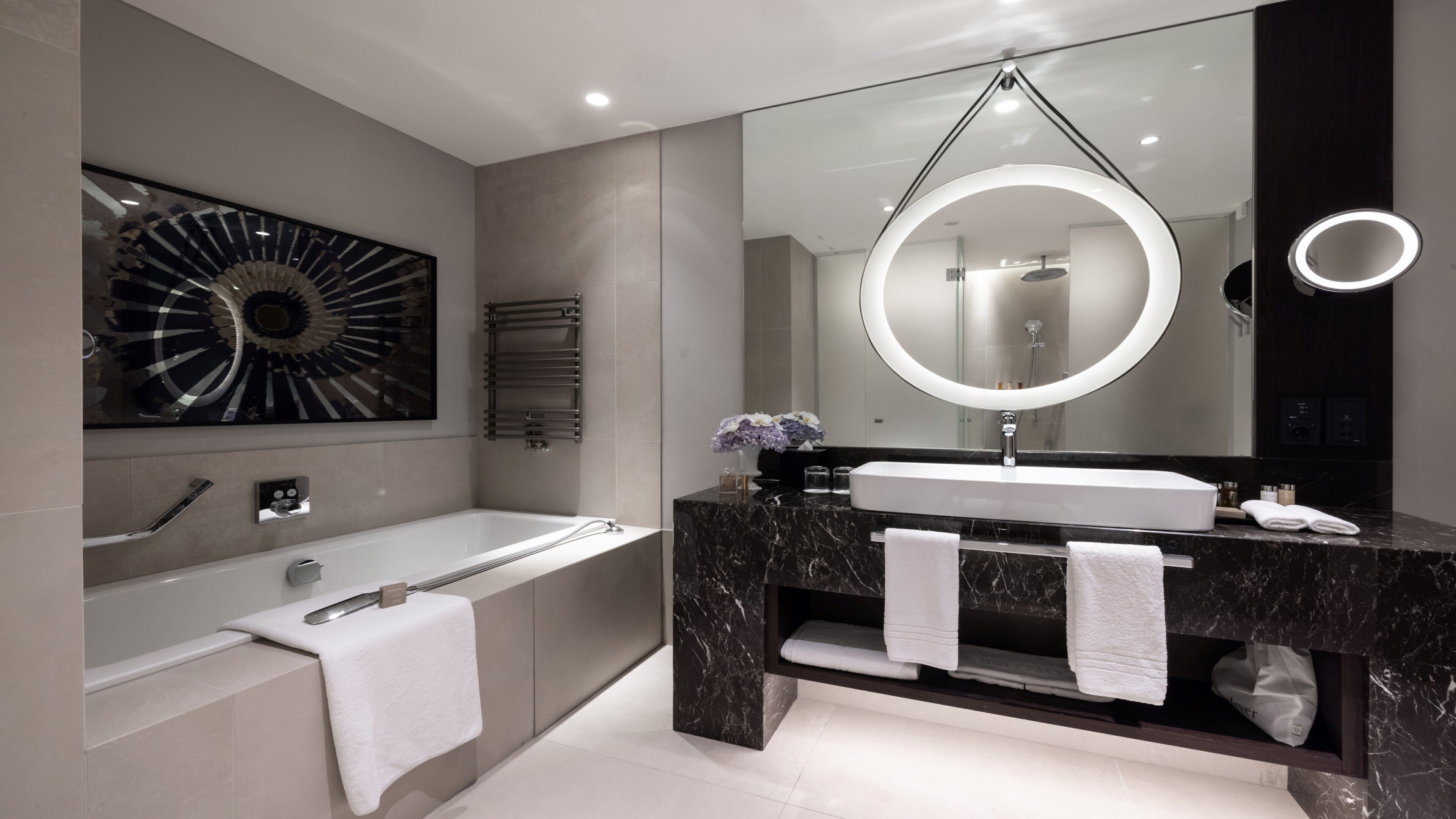 Une salle de bain moderne avec une baignoire, un meuble-lavabo avec un miroir et un porte-serviettes.