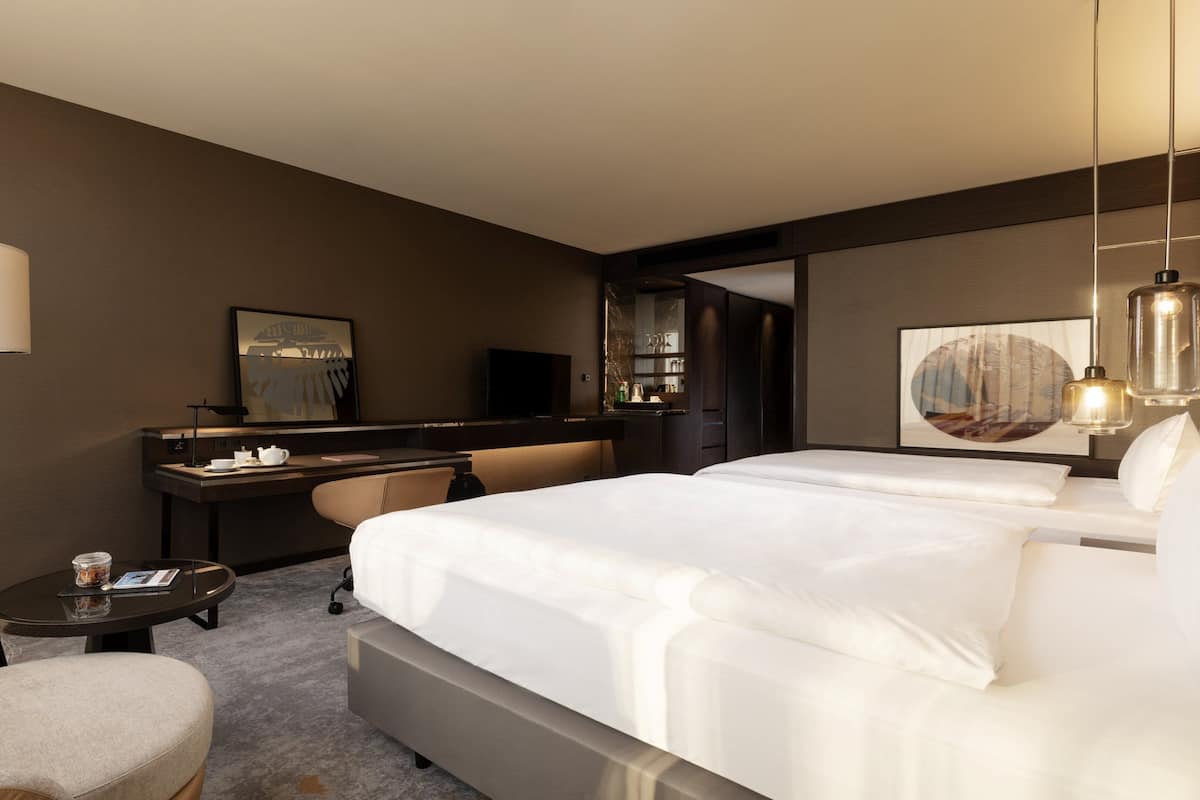 Een hotelkamer met een groot bed, een bureau, een stoel, een lamp en een televisie.