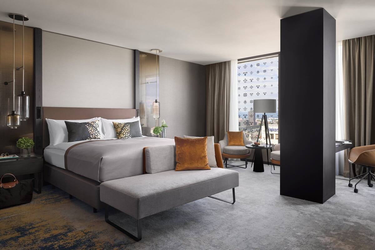 Een moderne hotelkamer met een groot bed, een bank, een bureau en uitzicht op de stad.