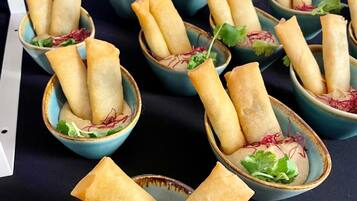 Una mesa con varios cuencos de rollitos de primavera, adornados con hojas verdes.