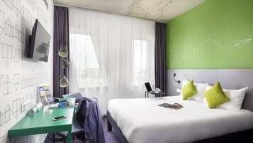 Een hotelkamer met een bed, bureau en een televisie aan de muur.