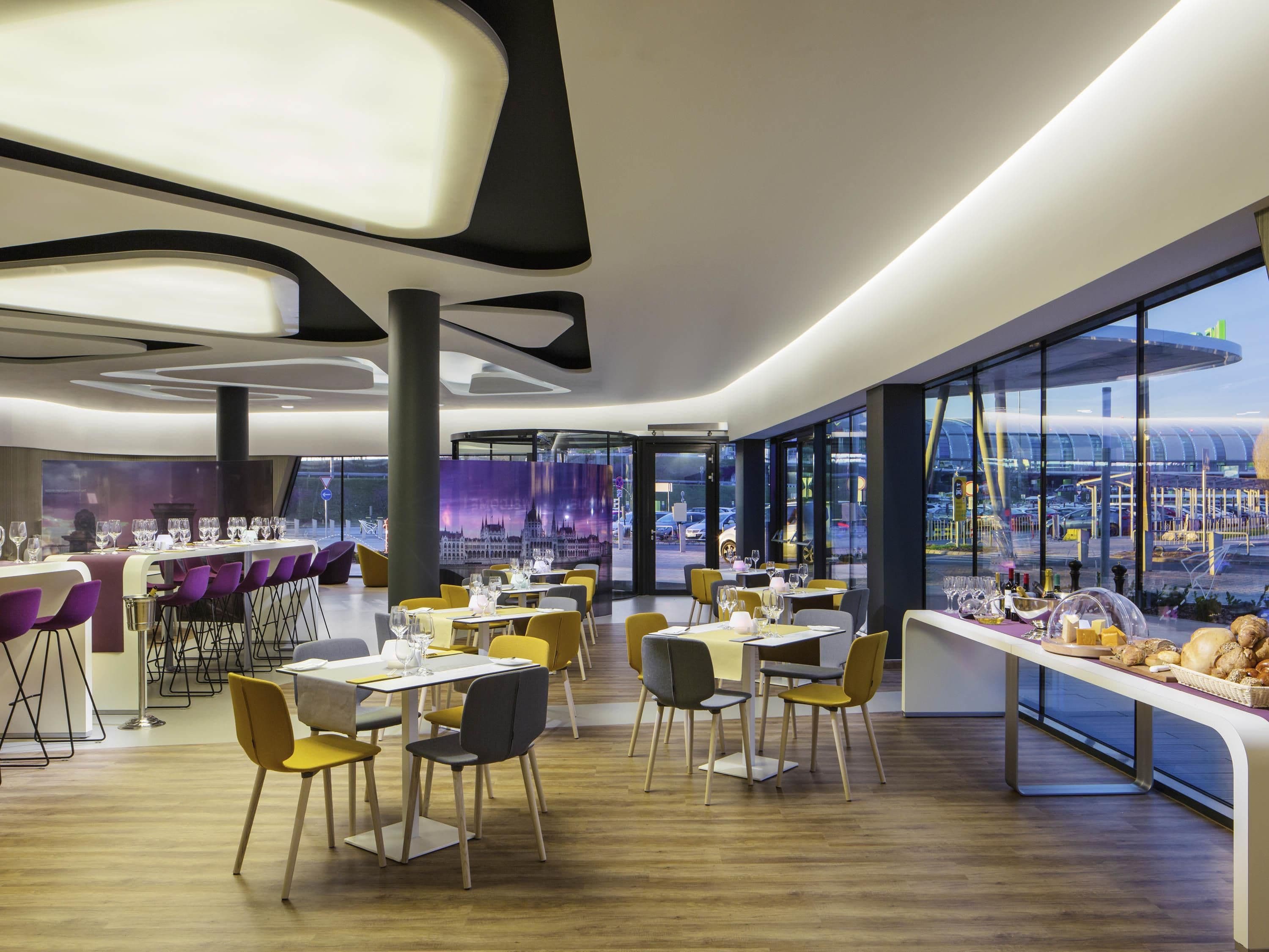 A modern restaurant with a view of a cityscape through large windows.