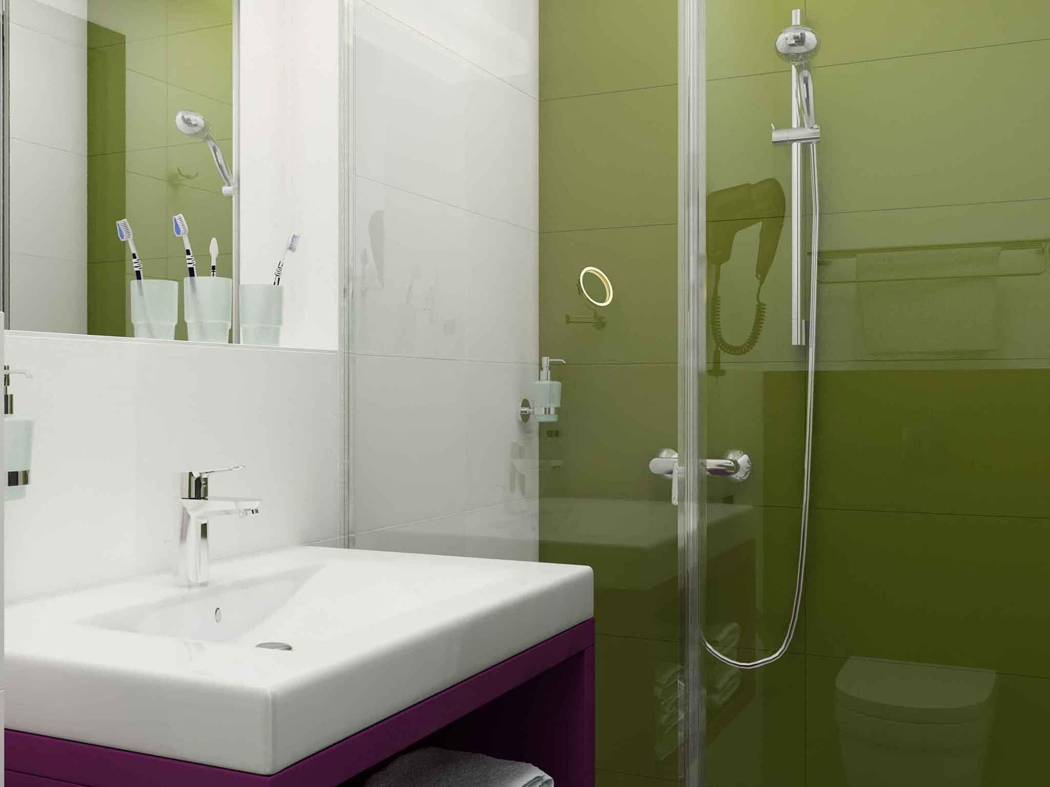 Ein Badezimmer mit einer gläsernen Duschkabine, einem weißen Waschbecken und einer violetten Kommode.