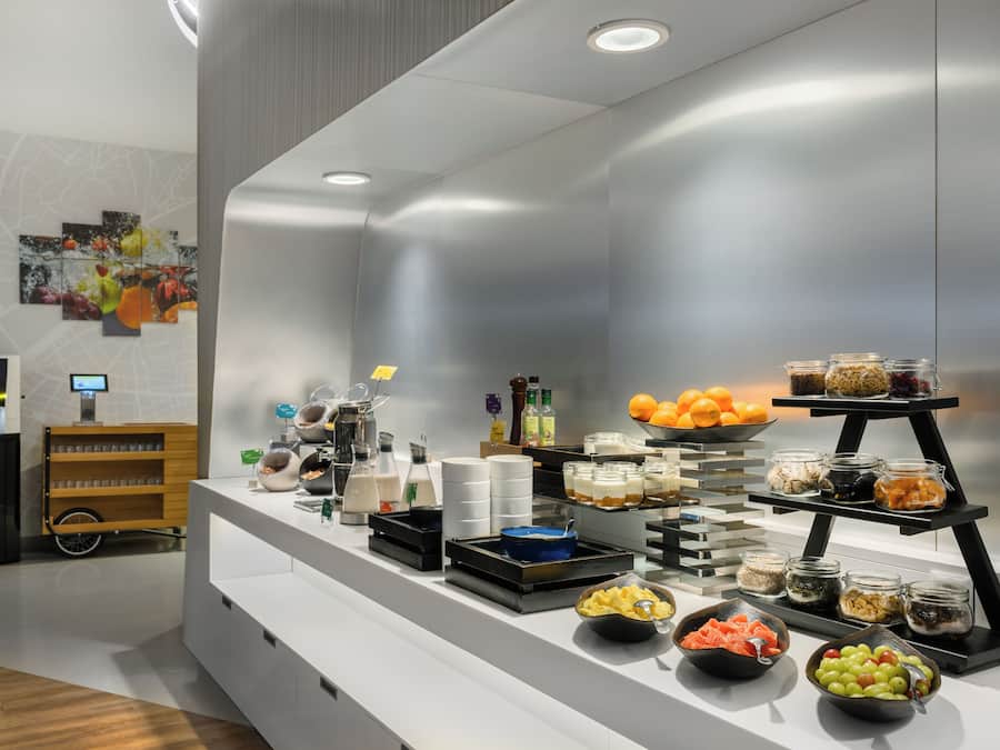 A buffet setup with various food items, a beverage dispenser, and a small cart with glasses.
