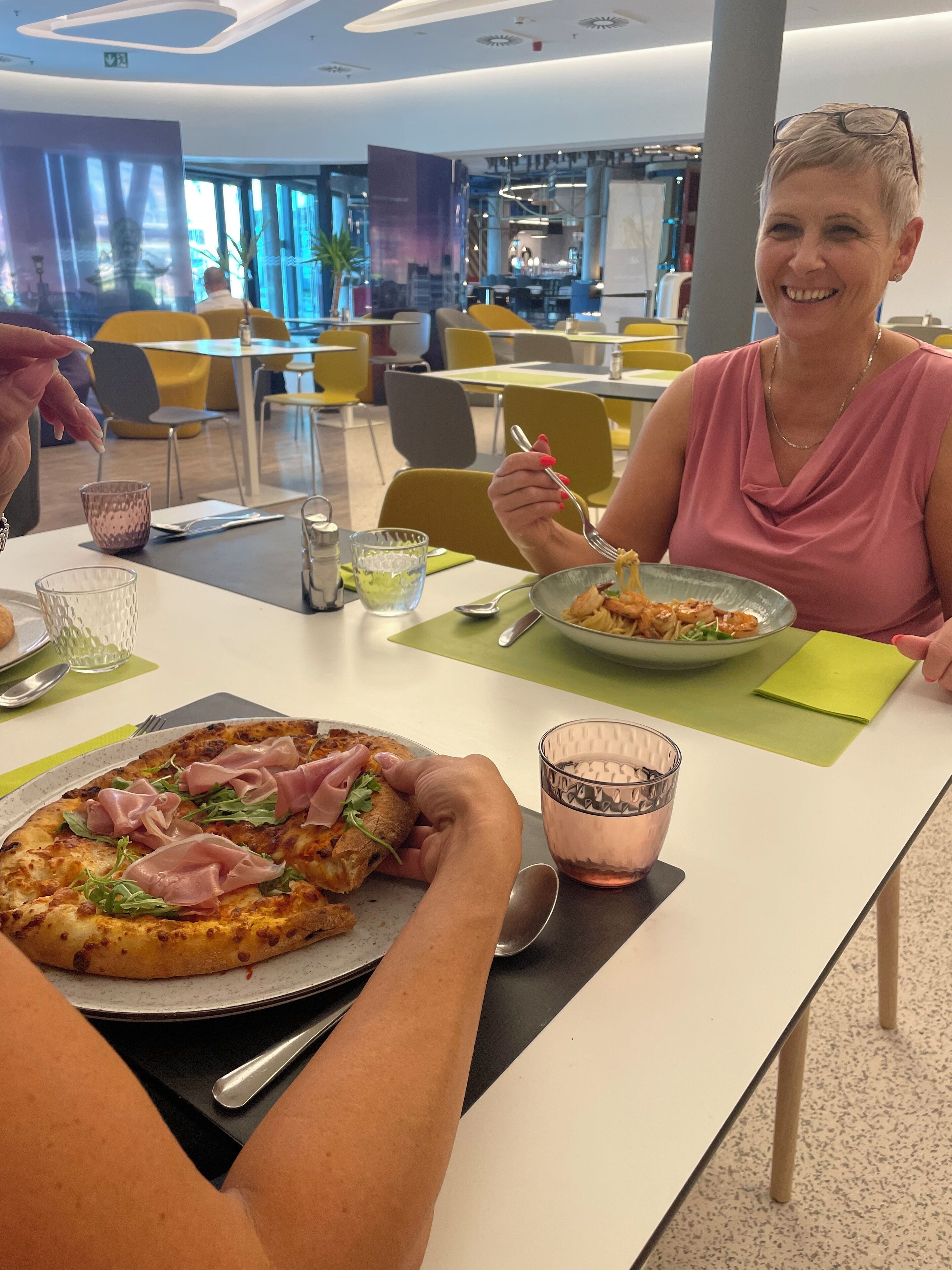 En matplats med en pizza, ett glas vatten och en person som äter.