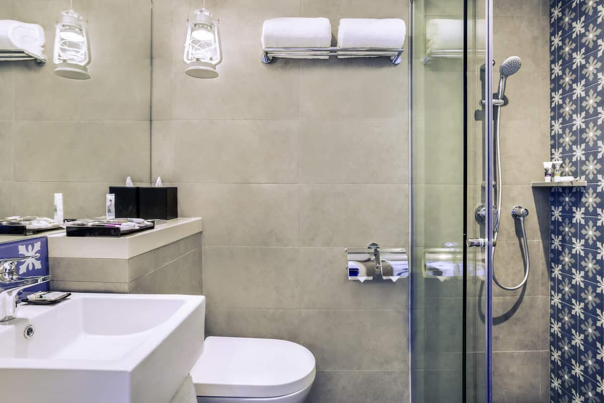 Uma casa de banho moderna com cabine de duche em vidro, uma sanita e uma pia branca.