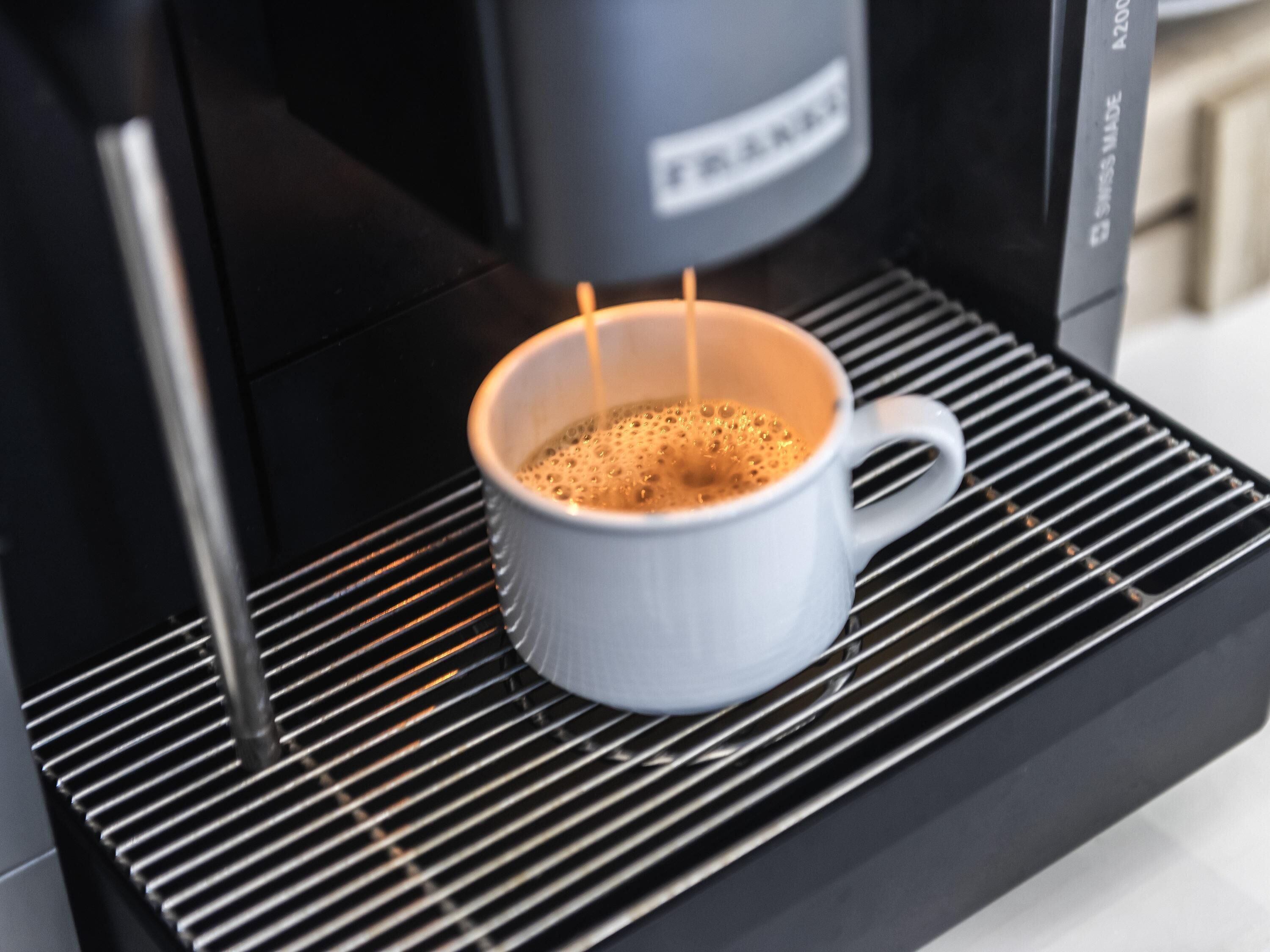 Una cafetera sirviendo café en una taza blanca.