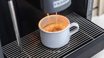 Una cafetera sirviendo café en una taza blanca.