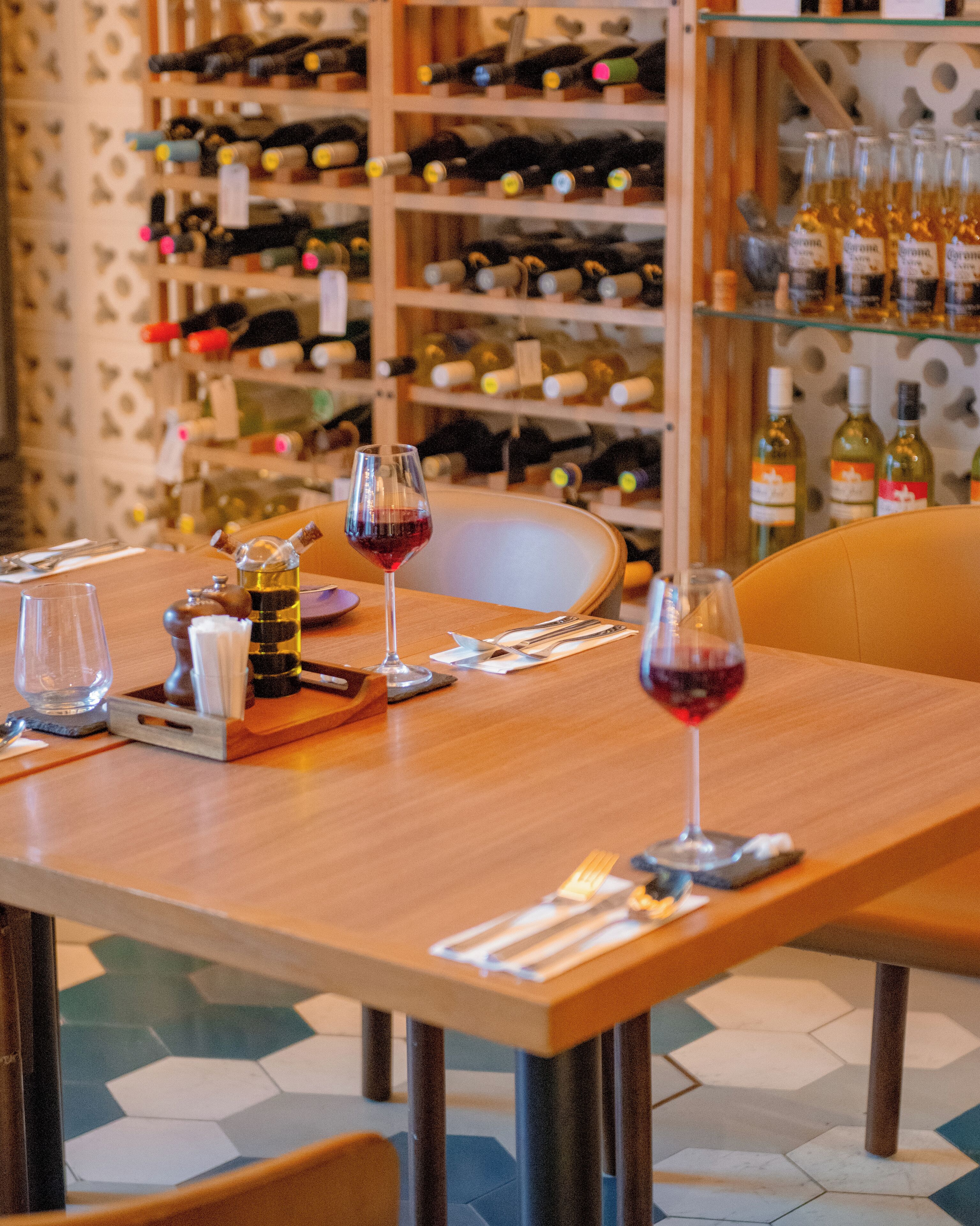 A dining table with wine glasses, a bottle of olive oil, and a menu.