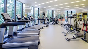 Moderni kuntosali, jossa on useita juoksumattoja, painonnostolaitteita ja kuntoiluvälineitä.