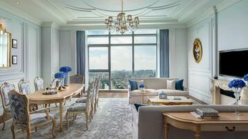 A spacious living room with a large window, elegant furniture, and a chandelier.