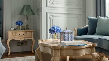 Una mesa de centro de madera con un jarrón de flores azules, una lámpara y libros.