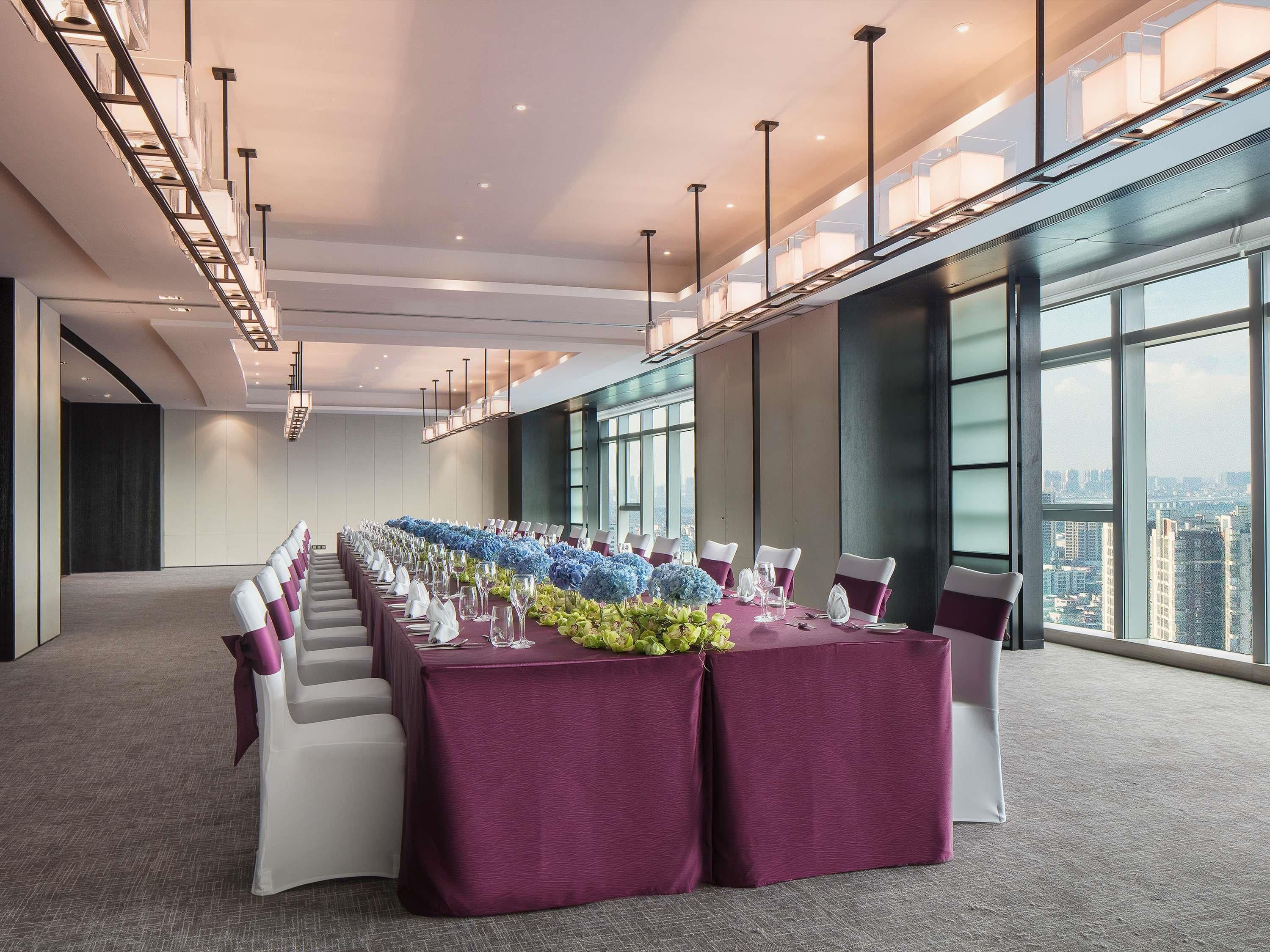 A conference room with a long table, chairs, and a city view.