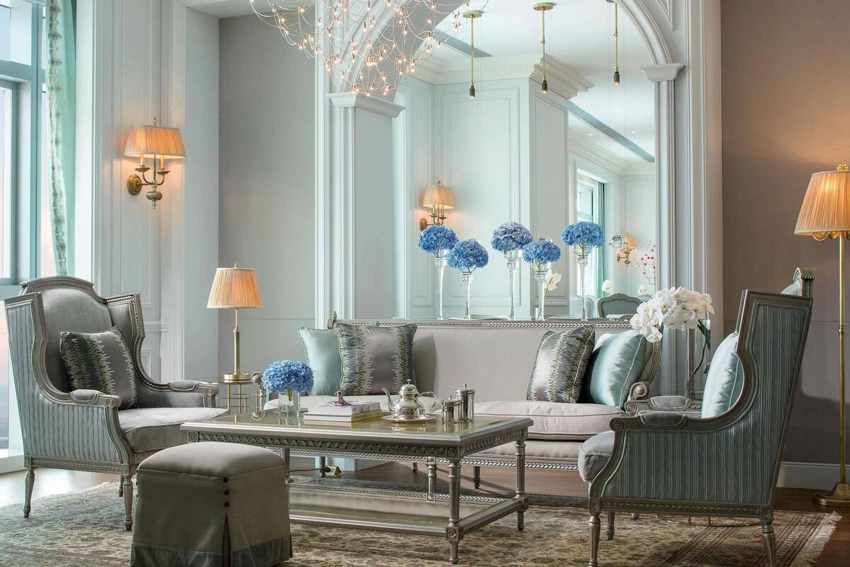 A spacious living room with a large mirror, elegant furniture, and decorative lighting.