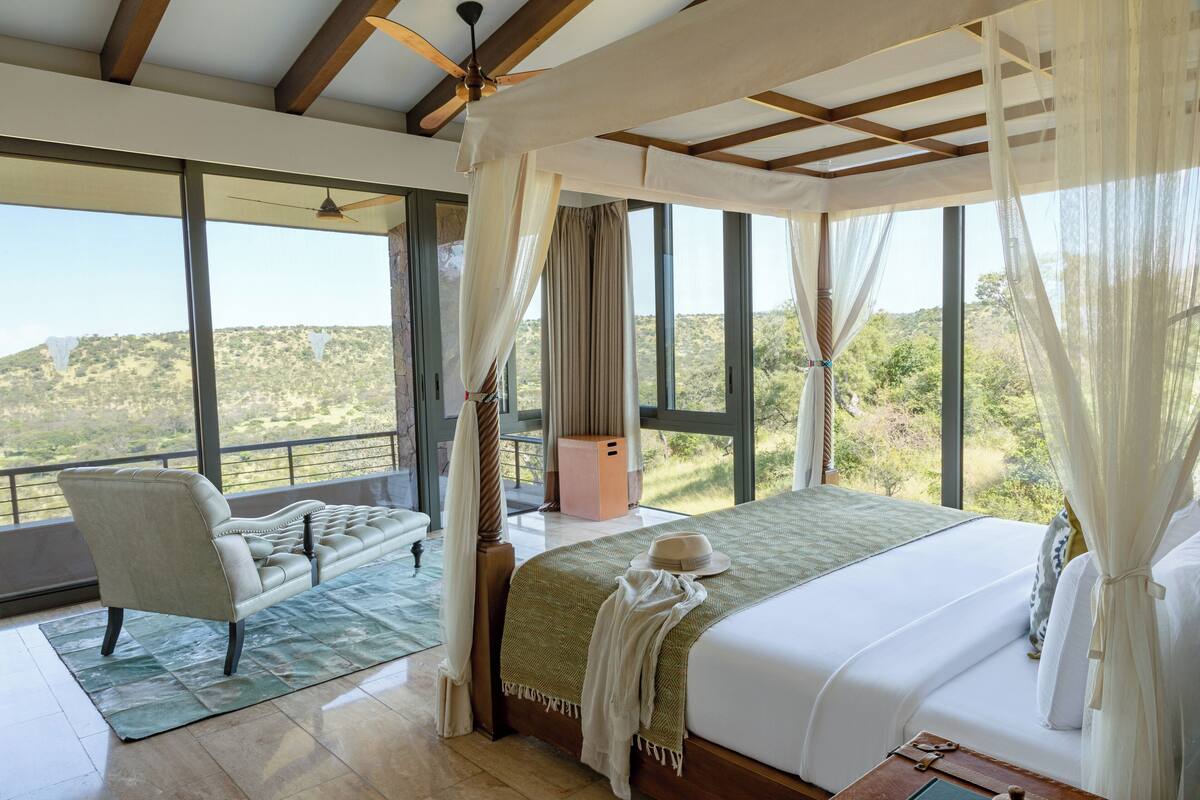 Une chambre avec un grand lit, une chaise et une vue sur l’extérieur.