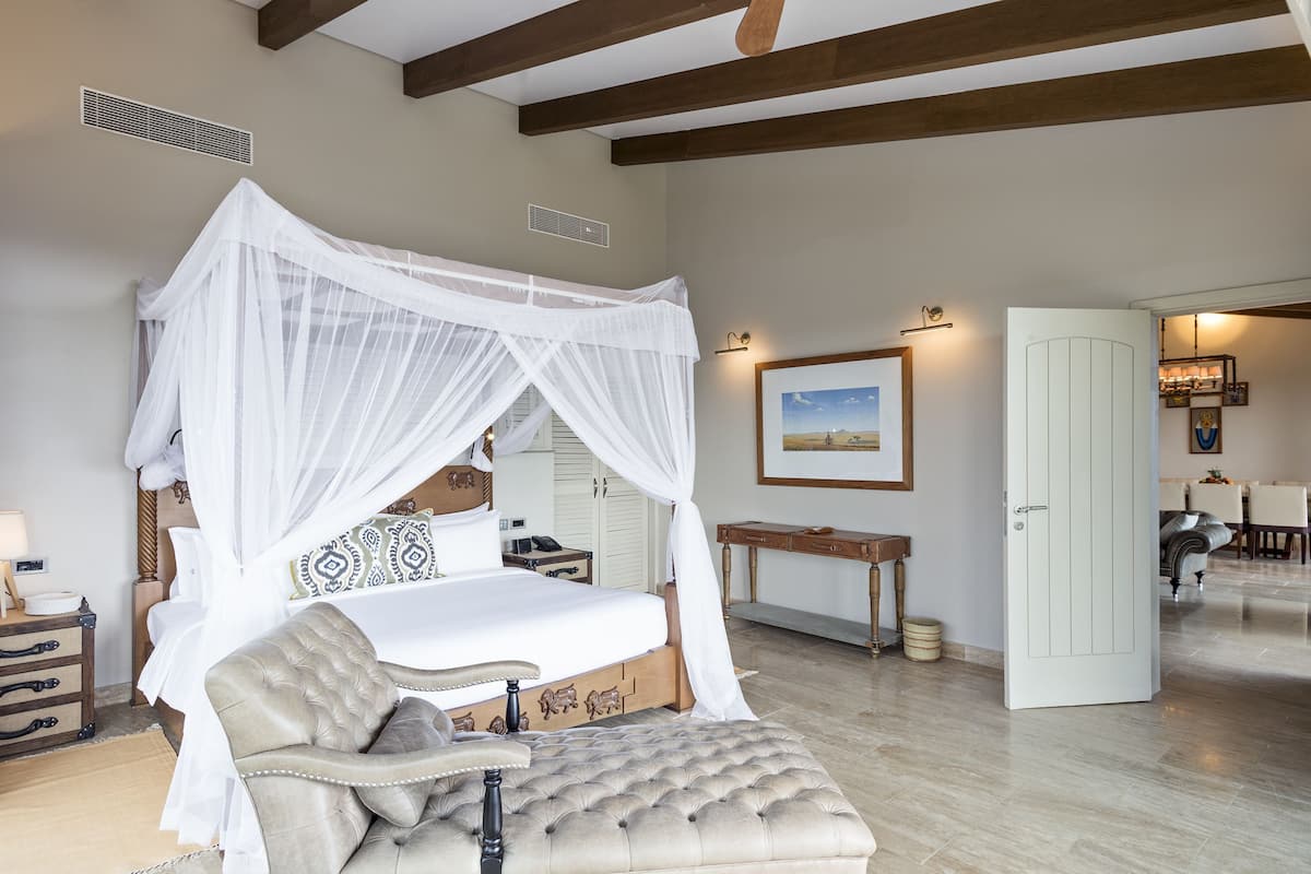Une chambre dotée d’un lit à baldaquin, d’un coin salon et d’un coin repas.