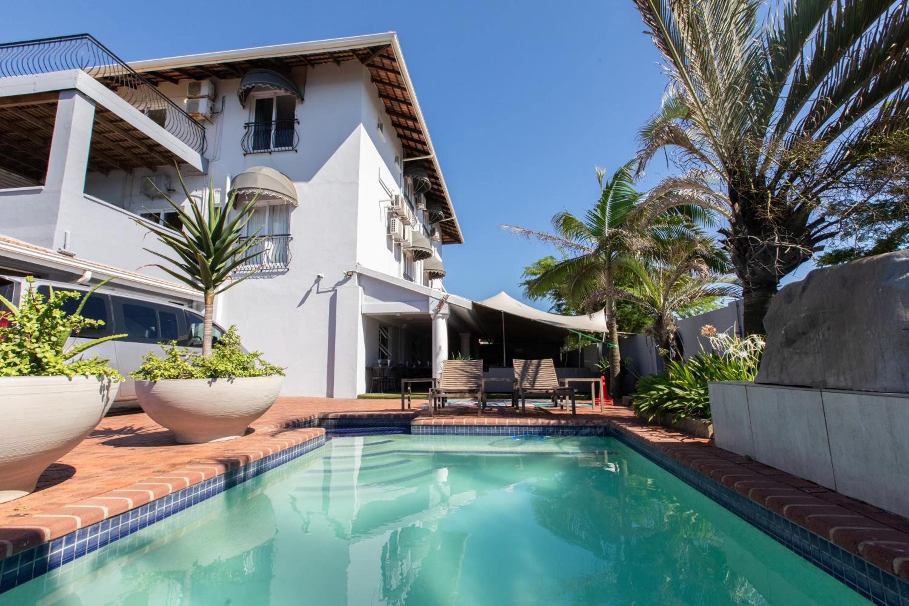 A residential property with a swimming pool, outdoor seating, and a covered patio area.