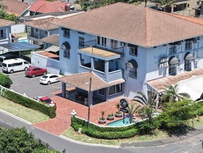 A two-story building with a tiled roof, a covered patio, and a swimming pool.