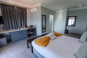 Ein Hotelzimmer mit Bett, Schreibtisch, Stuhl, Spiegel und Fenster.