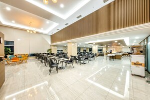 Un amplio comedor interior con varias mesas y sillas, una zona de cocina y un carrito de servicio identificado con la etiqueta 'kloud'.