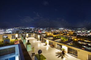 Une terrasse sur le toit offrant une vue sur la ville la nuit.