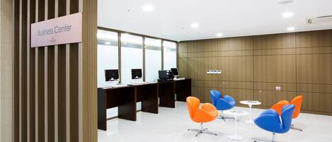 Centro de negocios con mostrador de recepción, computadoras y asientos modernos.