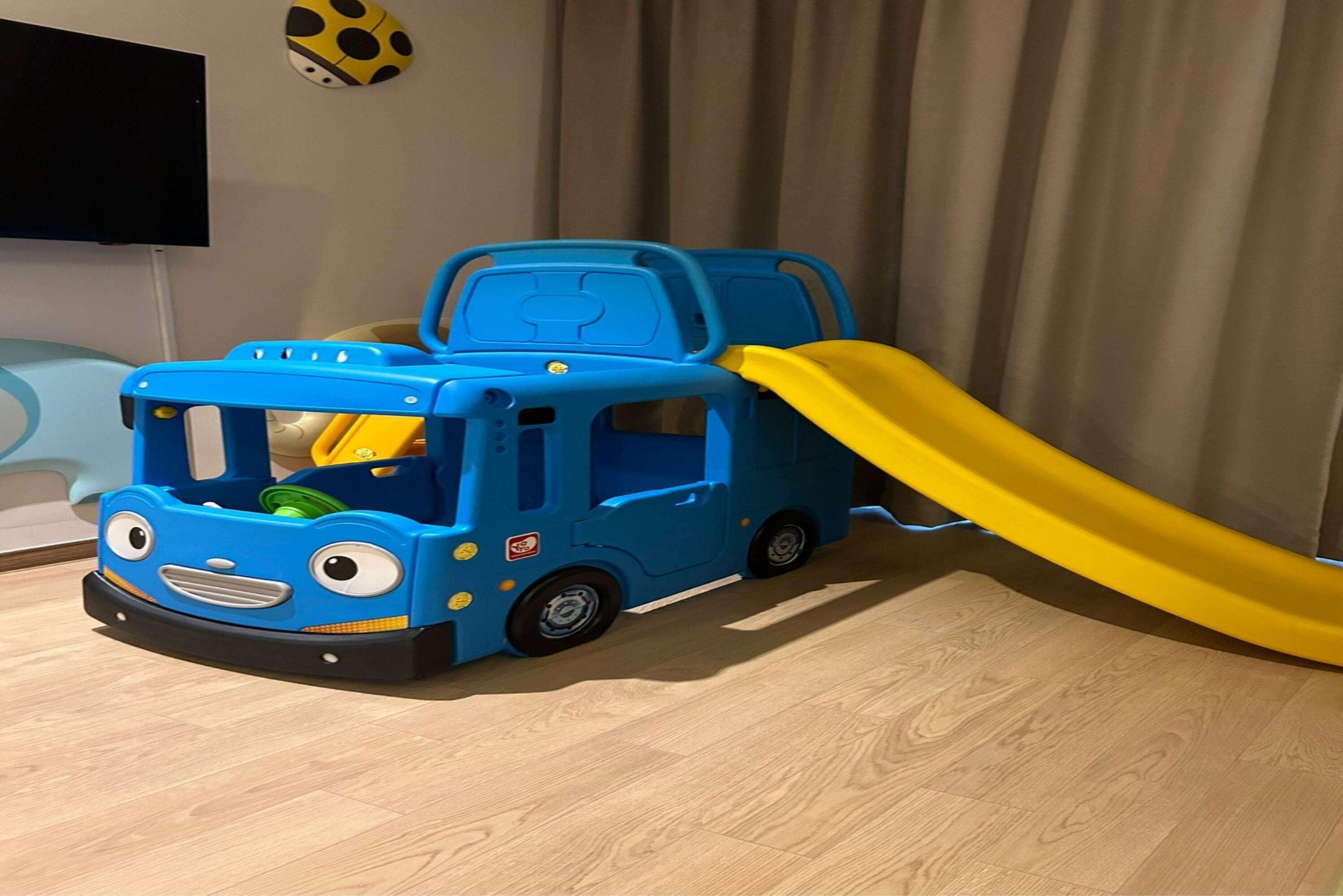 Un coche de juguete azul con un tobogán amarillo, sobre un suelo de madera.