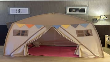 Un área de juegos tipo tienda de campaña, con dos ventanas y un tapete rojo en el suelo.