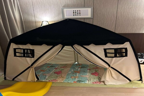 Un espace de jeux en forme de tente, avec un toboggan jaune et un sol à motifs.