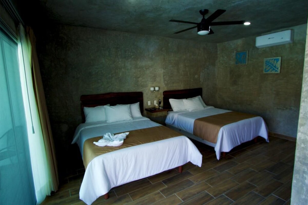 Une chambre d’hôtel avec deux lits, un ventilateur de plafond et une fenêtre avec des rideaux.