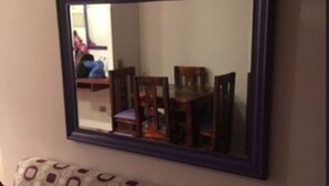 A living room with a patterned sofa, a large mirror, and a wooden table. - Departamento Belen Lira (Santiago)