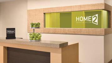En receptionsdisk med et skilt, der viser 'Hilton Honors', og et skilt med 'HOME 2 Suites by Hilton' over disken.