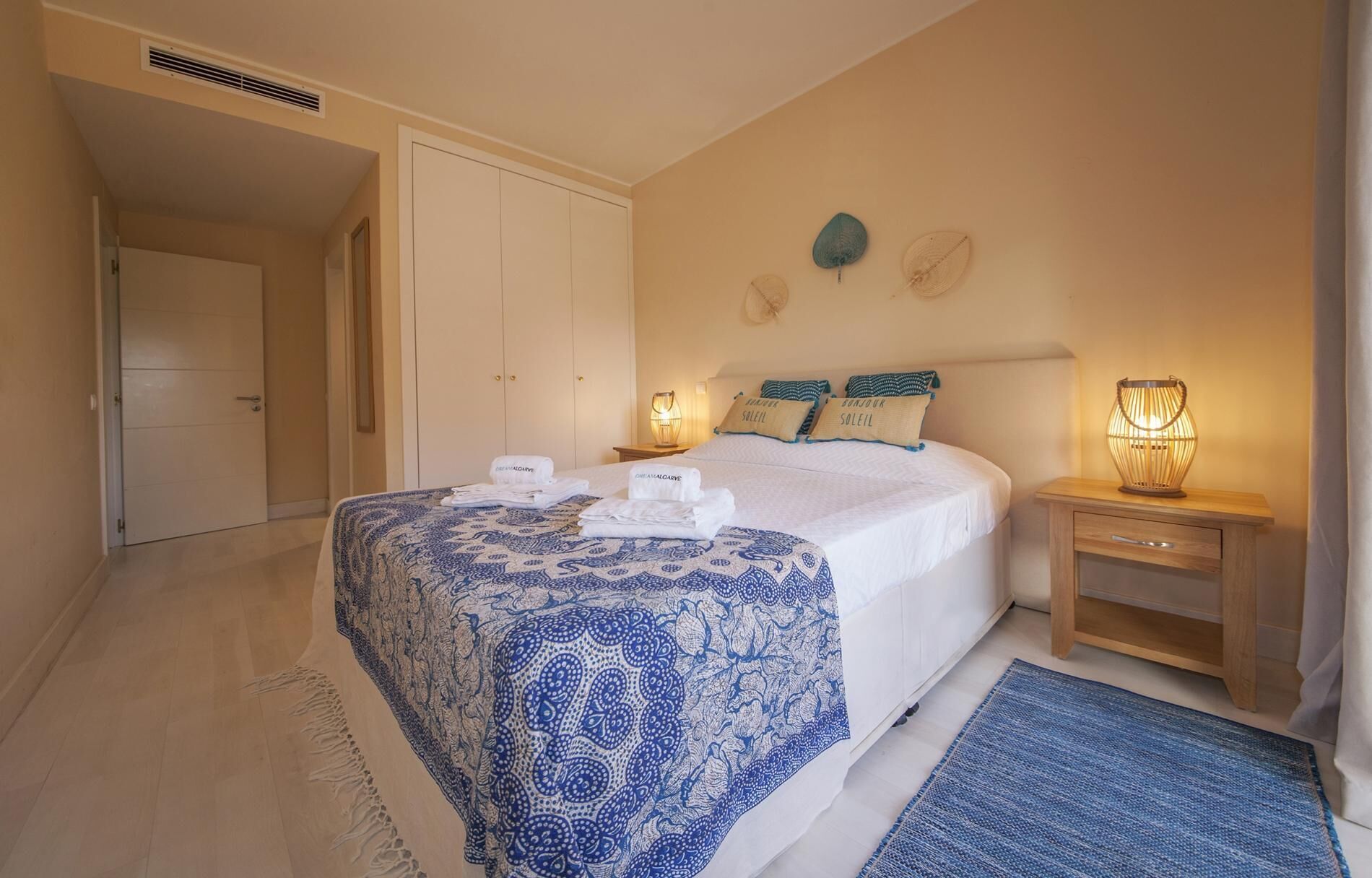 Un dormitorio con cama, mesitas de noche, lámpara y puerta.