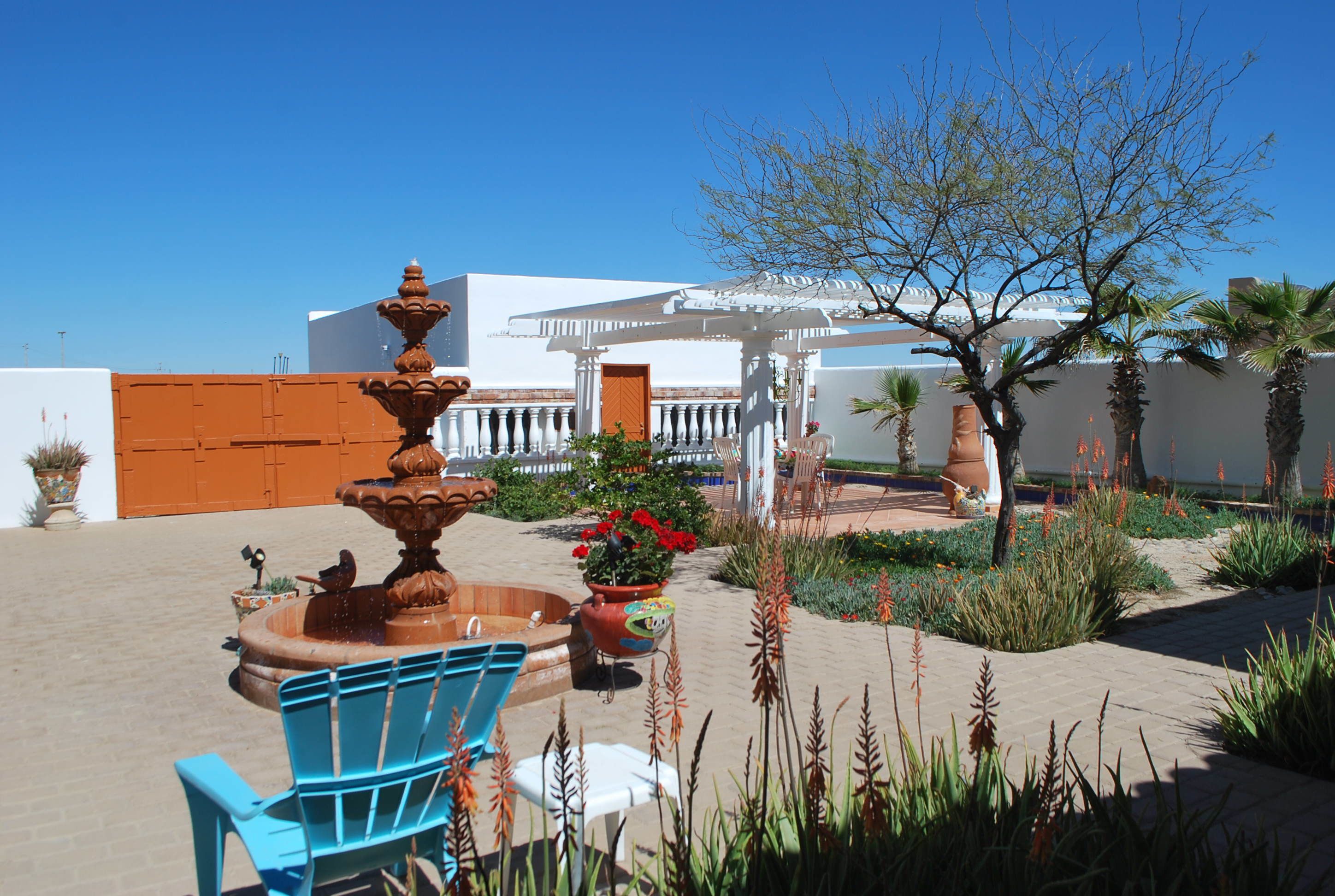 A courtyard with a fountain, outdoor seating, and a white building with a covered area.