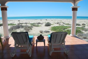 A beach view from a covered patio with two lounge chairs and a small table. - Casa de los Perros by Kivoya (Puerto Peñasco)