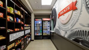 A snack aisle with shelves stocked with various packaged snacks and a refrigerated section with beverages. - Hampton Inn Brighton (Brighton)
