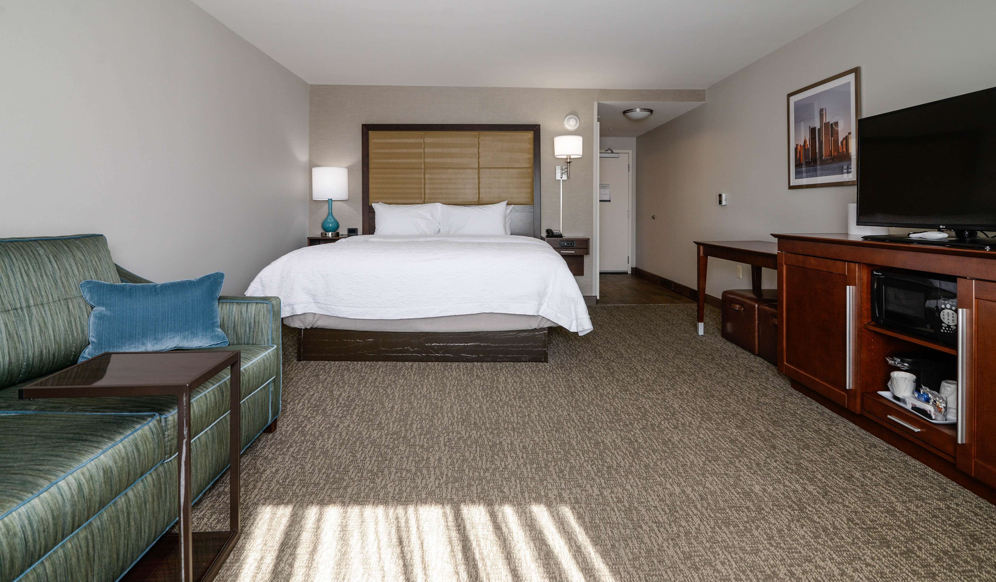 Ein Hotelzimmer mit Bett, Sofa, Fernseher, Mikrowelle und Schrank.