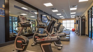 A gym with multiple treadmills, exercise bikes, and a weight machine. - Hampton Inn Brighton (Brighton)