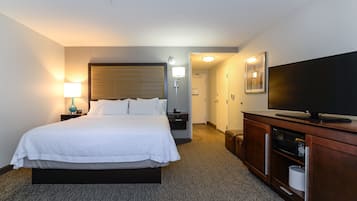 A hotel room with a large bed, bedside lamps, a television, a microwave, and a cabinet.