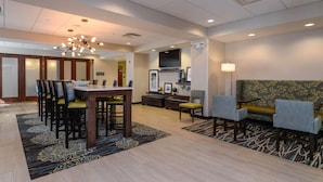 A hotel lobby with a dining area, seating, a TV, and a fireplace. - Hampton Inn Brighton (Brighton)