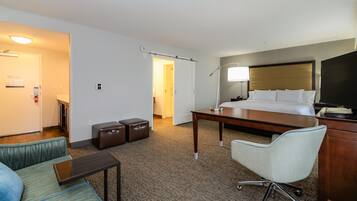 A hotel room with a bed, desk, chair, and a television.