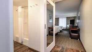 A hotel room with a shower, a bed, a desk, and a mirror. - Hampton Inn Brighton (Brighton)