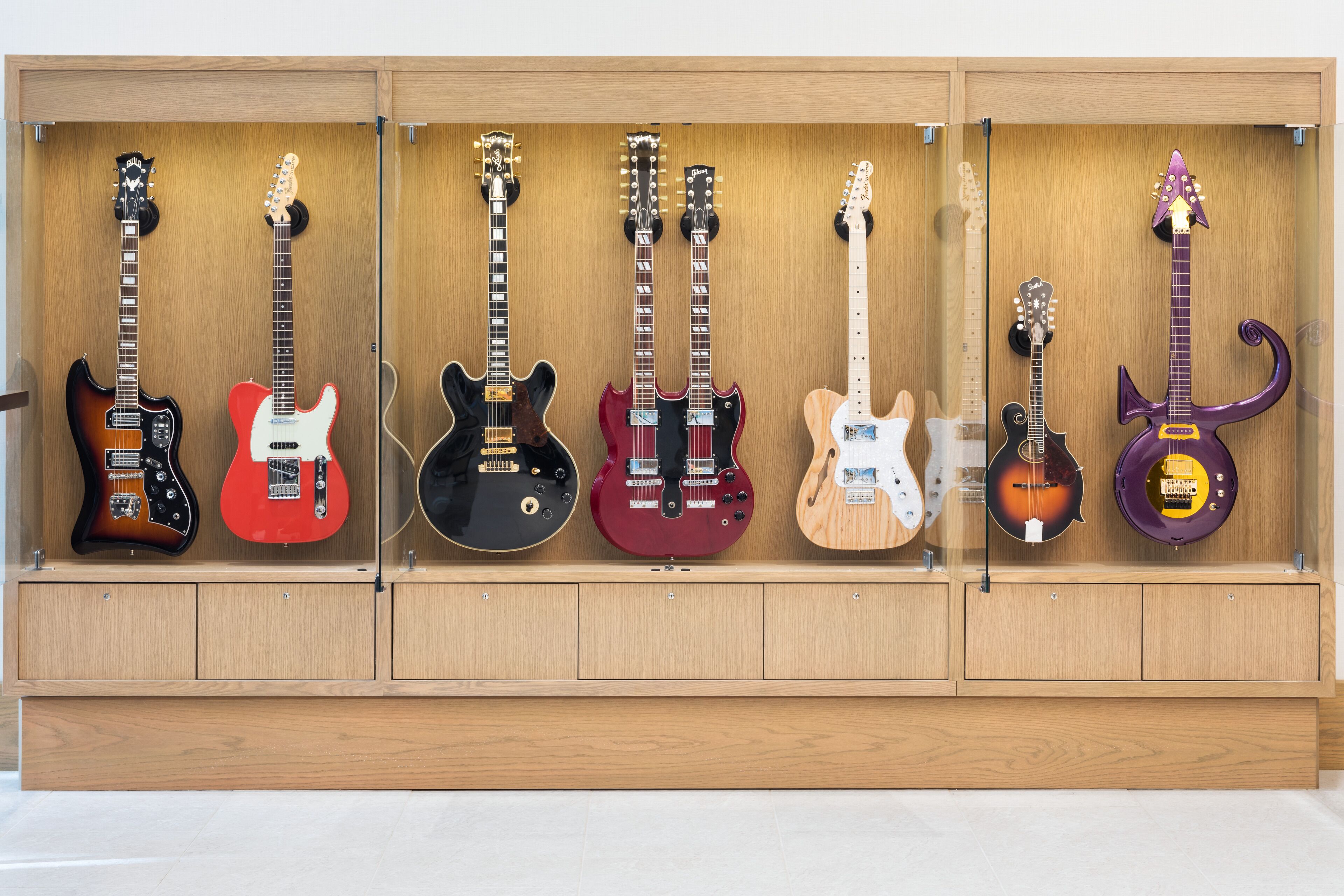 Un expositor de madera con seis guitarras eléctricas de distintos colores y diseños.