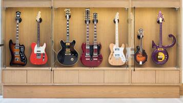A wooden display case with six electric guitars of various colors and designs.