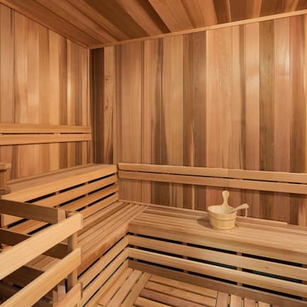 A sauna with wooden benches and a small table with a container.